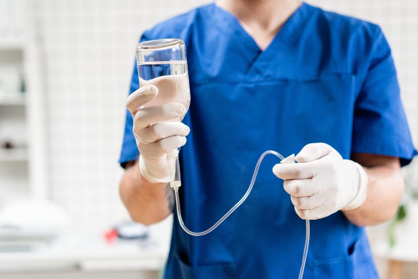 Medical professional in blue scrubs preparing an IV drip for hydration therapy in Pompano Beach, FL.